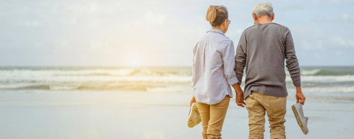 image with two elderly people walking along a beach