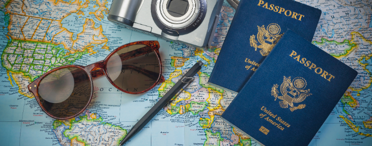 image of a map with other items layed out over it, the items are passports, sunglasses, a pen and a digital camera