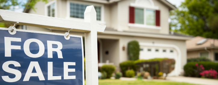 Image shows a for sale sign in front of a house