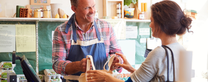 local shop owner hands a bag to a customer