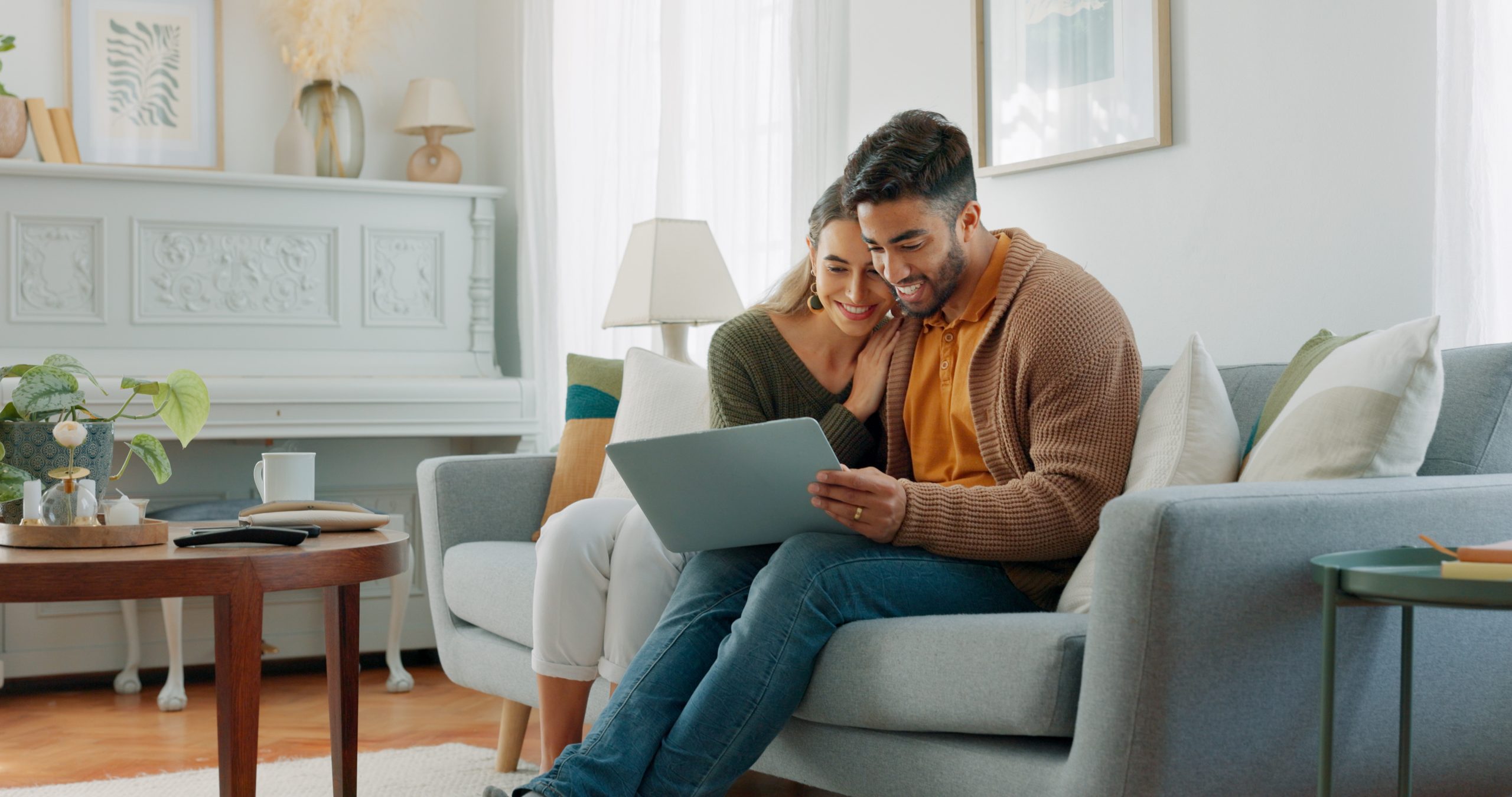 Laptop, living room and couple search website information for home investment, loan or real estate property discussion on sofa. Young people on couch with pc internet, planning future together.