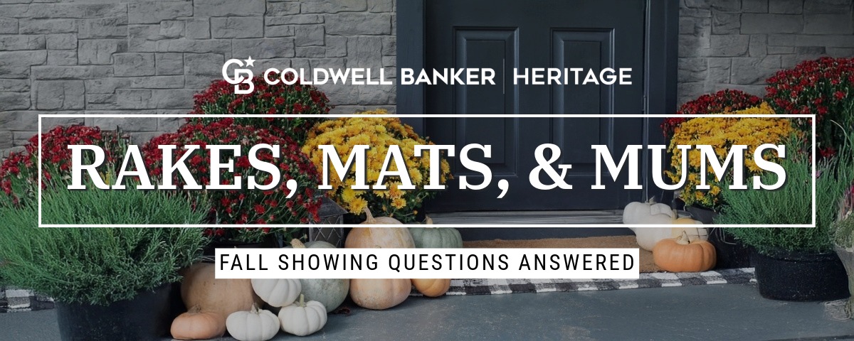 Front porch styled for fall with pumpkins, colorful mums, and a welcome mat at a dark entry door.