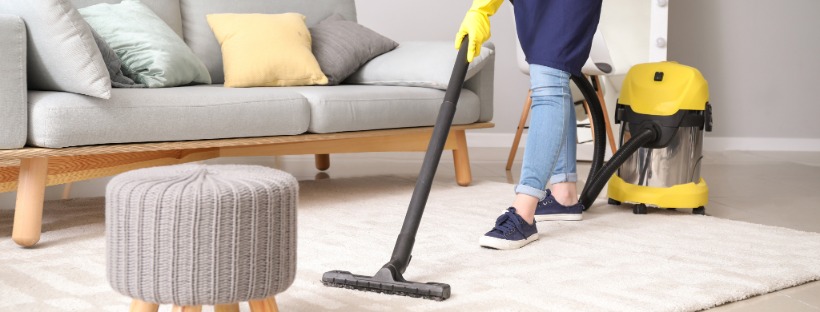 A home-cleaning professional vacuums a carpeted living room, showcasing local service providers available through CB Preferred Providers.