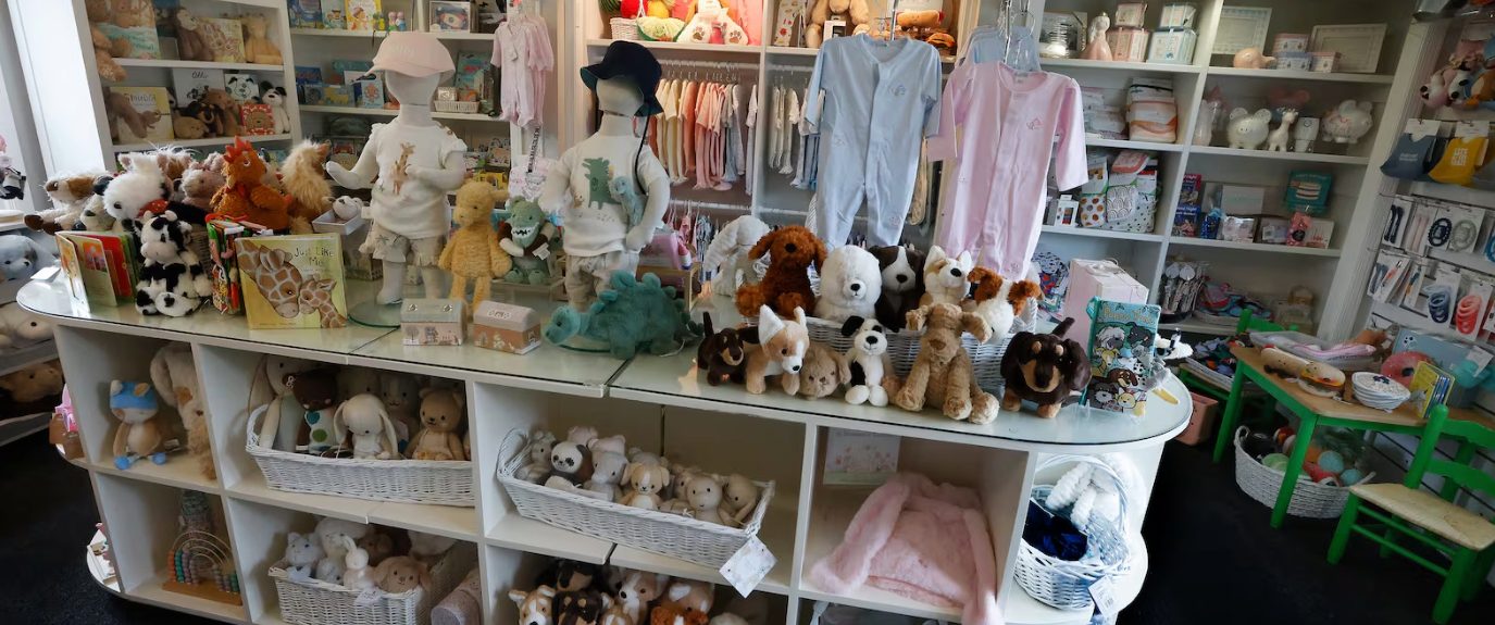 Interior of The Little Exchange in Oakwood showing shelves of children’s clothing, plush toys, books, and baby gifts arranged in a bright boutique.