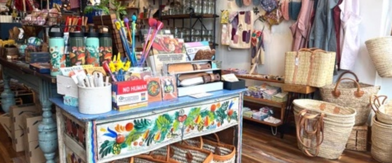 Colorful display inside Pink Moon Goods featuring artisan home decor, reusable goods, stationery, woven baskets, and sustainable gift items.